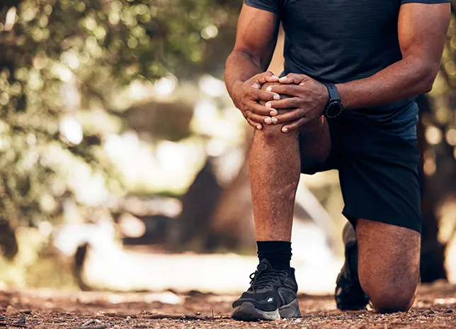 man kneeling on trail
